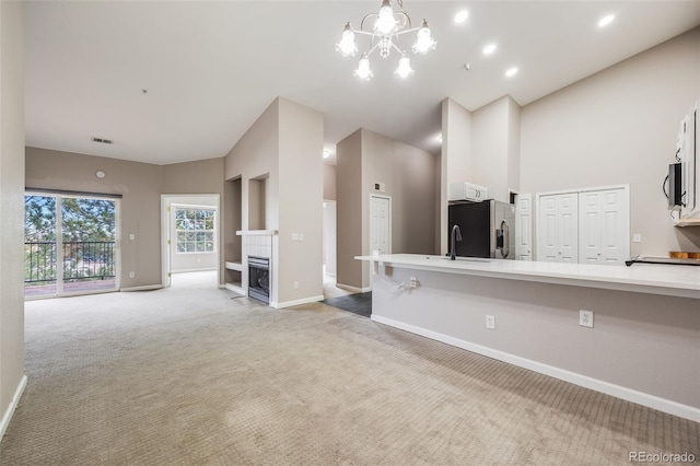 unfurnished living room featuring a high ceiling, light colored carpet, and an inviting chandelier