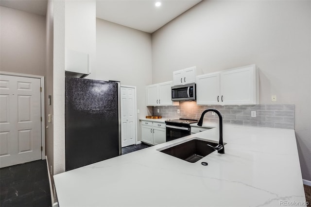 kitchen featuring black refrigerator, white cabinetry, range with electric stovetop, and light stone counters