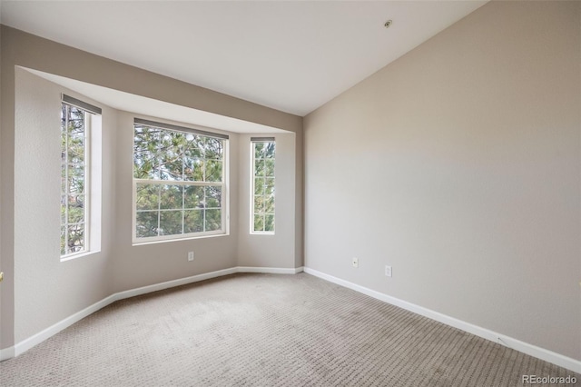 carpeted spare room featuring vaulted ceiling