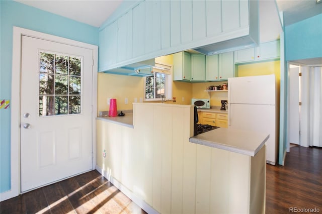 kitchen with dark wood-type flooring, kitchen peninsula, green cabinets, and white appliances