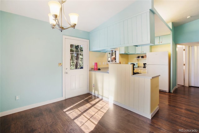 kitchen featuring dark hardwood / wood-style flooring, kitchen peninsula, lofted ceiling, decorative light fixtures, and white fridge