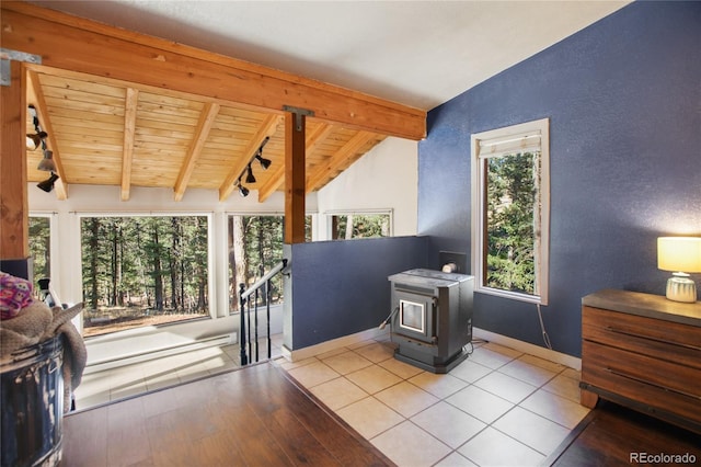 interior space with light hardwood / wood-style floors, a wood stove, vaulted ceiling with beams, and wood ceiling