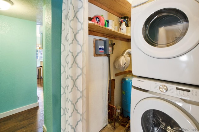 washroom with stacked washer and dryer and dark hardwood / wood-style flooring