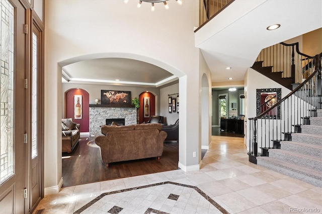 9065 E Lost Hill Trl, Lone Tree, CO 80124 - foyer with a stone fireplace, stairway, inlaid floor details, arched walkways, and recessed lighting