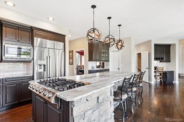 9065 E Lost Hill Trl, Lone Tree, CO 80124 - kitchen featuring built in appliances, backsplash, dark wood-style floors, a chandelier, and a spacious island