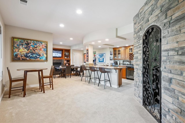 9065 E Lost Hill Trl, Lone Tree, CO 80124 - kitchen featuring a breakfast bar area, beverage cooler, light colored carpet, brown cabinets, and recessed lighting