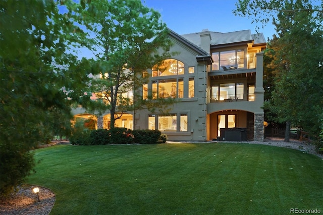 9065 E Lost Hill Trl, Lone Tree, CO 80124 - back of property with a balcony, a hot tub, a lawn, and stucco siding