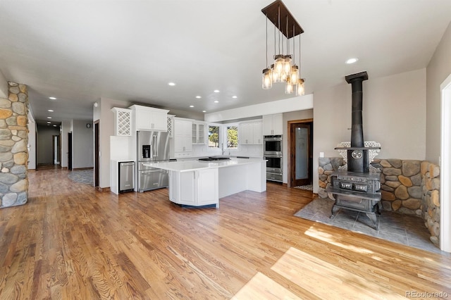 kitchen with a kitchen island, light wood-type flooring, appliances with stainless steel finishes, and white cabinetry