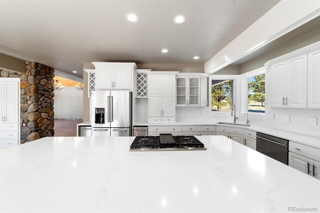 kitchen with sink, appliances with stainless steel finishes, white cabinetry, and light stone countertops