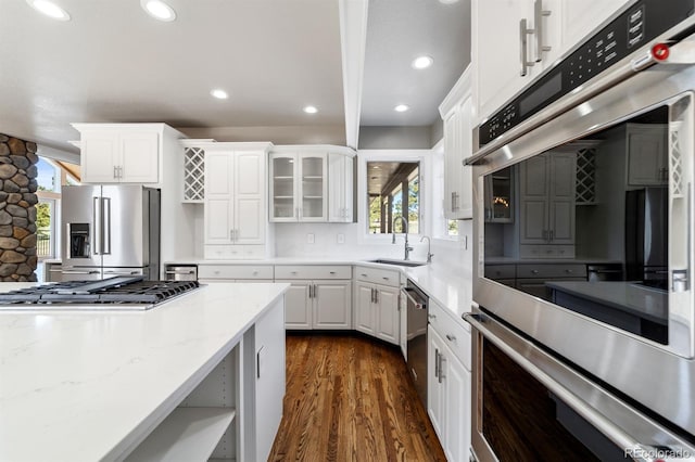 kitchen featuring white cabinets, dark wood-type flooring, appliances with stainless steel finishes, sink, and light stone counters