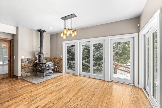 interior space featuring french doors, a wood stove, an inviting chandelier, and light wood-type flooring