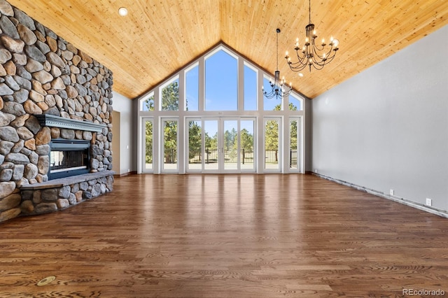 unfurnished living room featuring high vaulted ceiling, dark wood-type flooring, a notable chandelier, and a stone fireplace