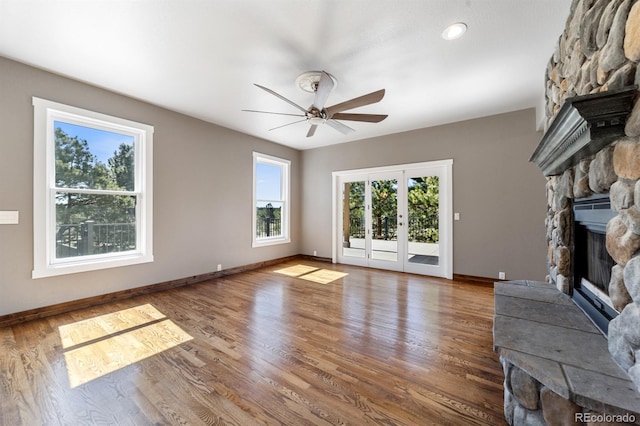 unfurnished living room featuring french doors, dark hardwood / wood-style flooring, ceiling fan, and a fireplace