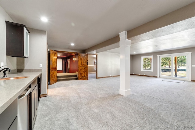 kitchen featuring sink, decorative columns, light carpet, and stainless steel dishwasher