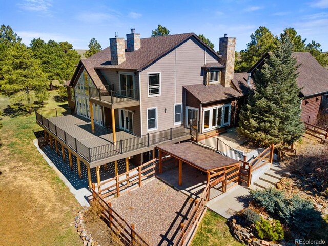 rear view of house with a lawn, a balcony, a wooden deck, and a patio