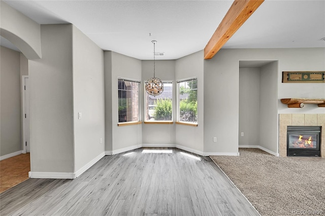 5220 Boardwalk Dr Unit A14, Fort Collins, CO 80525 - unfurnished dining area with beam ceiling, wood finished floors, arched walkways, a fireplace, and a chandelier