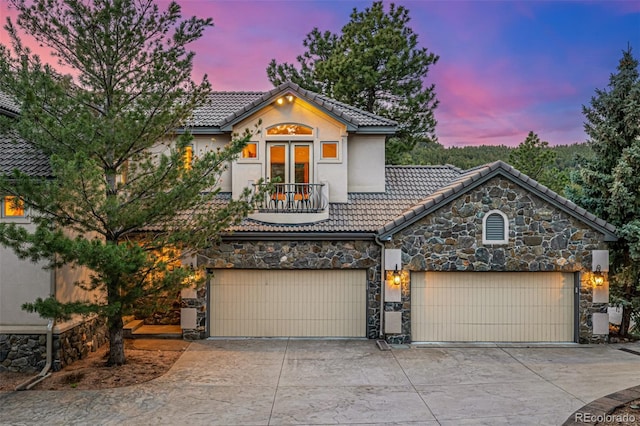 22554 Treetop Ln, Golden, CO 80401 - view of front facade featuring stone siding, driveway, a tiled roof, french doors, and stucco siding