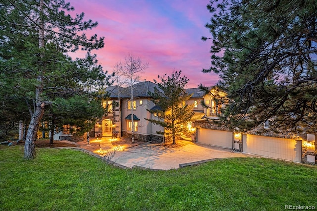 22554 Treetop Ln, Golden, CO 80401 - view of front of property with a front lawn, stucco siding, an attached garage, stone siding, and concrete driveway