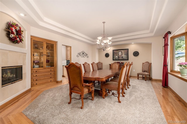 22554 Treetop Ln, Golden, CO 80401 - dining space featuring a raised ceiling, a chandelier, light wood-style floors, a fireplace, and baseboards