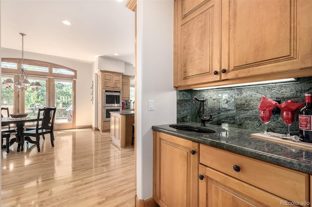 22554 Treetop Ln, Golden, CO 80401 - indoor wet bar featuring stainless steel double oven, tasteful backsplash, baseboards, light wood-style floors, and a chandelier