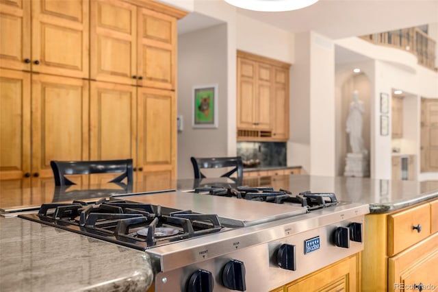 22554 Treetop Ln, Golden, CO 80401 - kitchen with stainless steel gas cooktop, tasteful backsplash, and light brown cabinetry