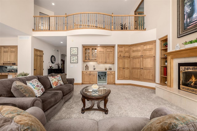 22554 Treetop Ln, Golden, CO 80401 - carpeted living area featuring wine cooler, built in features, a towering ceiling, a fireplace, and baseboards
