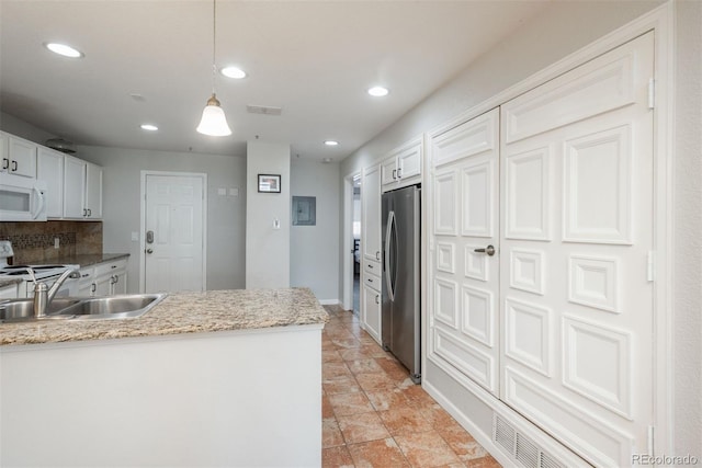 kitchen featuring stainless steel appliances, white cabinetry, decorative light fixtures, and decorative backsplash