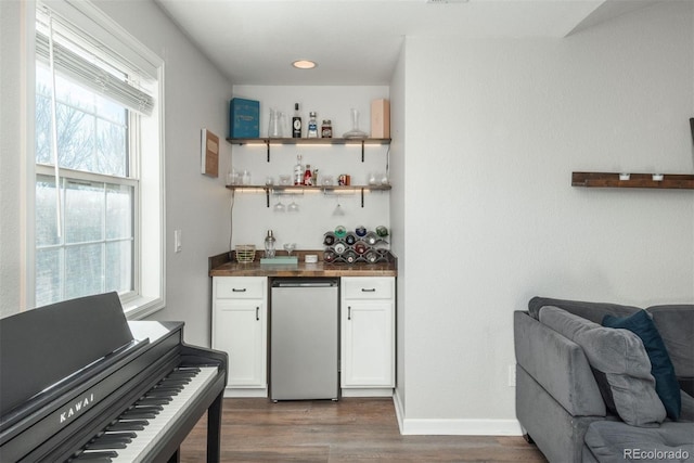 bar featuring white cabinetry, dark wood-type flooring, and stainless steel refrigerator