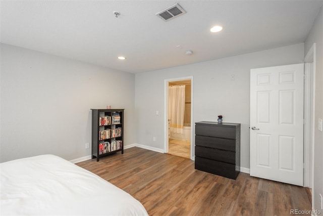 bedroom with ensuite bathroom and dark hardwood / wood-style flooring