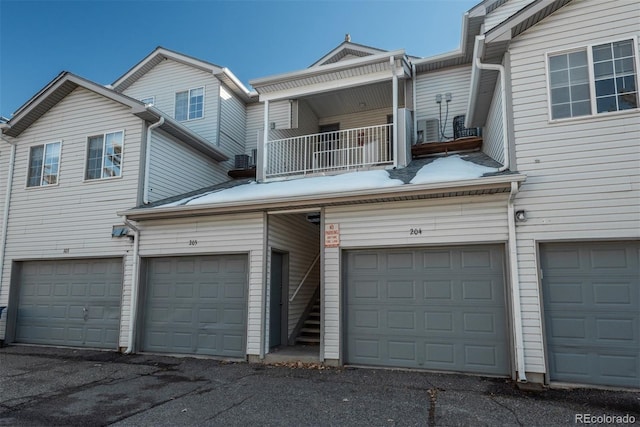 view of front facade with a garage, central AC unit, and a balcony