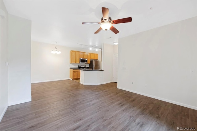 unfurnished living room featuring track lighting, ceiling fan with notable chandelier, baseboards, and wood finished floors