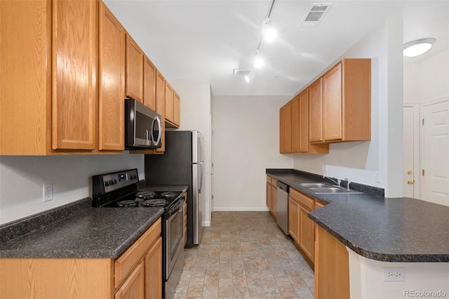 kitchen with visible vents, a peninsula, a sink, stainless steel appliances, and dark countertops