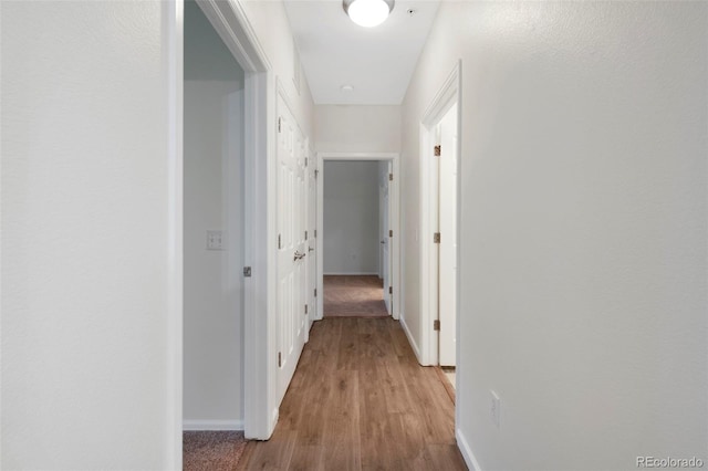 hall featuring baseboards and light wood-style floors