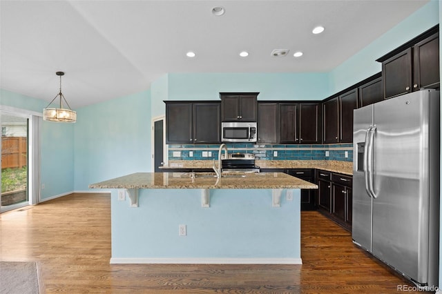 4732 S Coolidge St, Aurora, CO 80016 - kitchen with stainless steel appliances, light stone counters, decorative backsplash, a breakfast bar area, and a kitchen island with sink