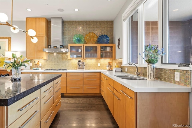 kitchen featuring wall chimney exhaust hood, backsplash, dark wood-type flooring, and sink