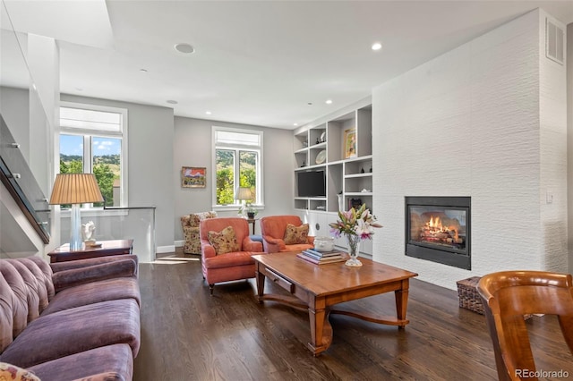 living room with built in shelves, hardwood / wood-style flooring, and a healthy amount of sunlight