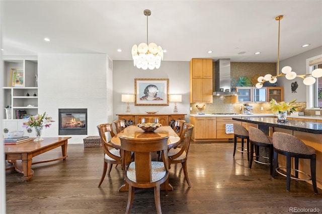 dining space with a fireplace, a chandelier, and dark hardwood / wood-style flooring