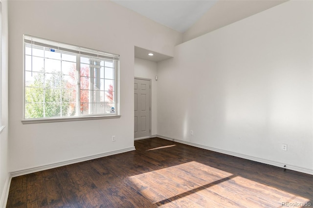 unfurnished room featuring dark wood-type flooring and lofted ceiling