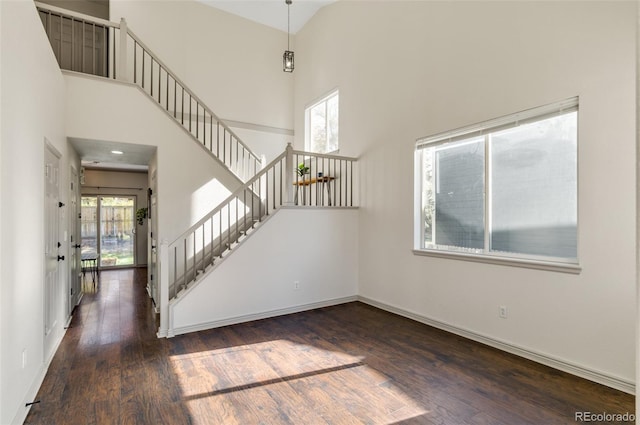 interior space with hardwood / wood-style flooring, a healthy amount of sunlight, and a towering ceiling