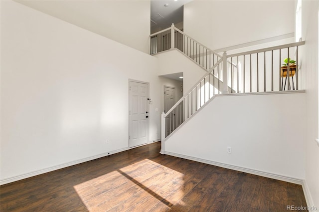 interior space with dark wood-type flooring and a towering ceiling