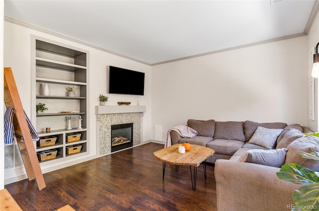 living room with dark wood-type flooring, ornamental molding, and built in shelves