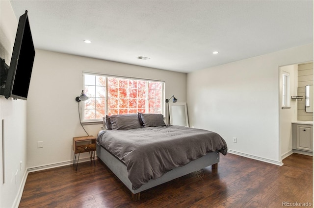 bedroom featuring a textured ceiling, connected bathroom, and dark hardwood / wood-style flooring