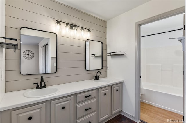 bathroom featuring vanity, wood walls, wood-type flooring, and bathing tub / shower combination