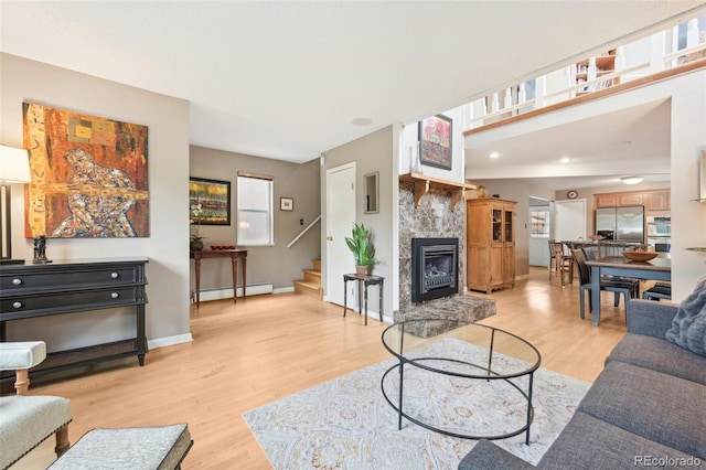 living room with a tiled fireplace, a baseboard radiator, and light hardwood / wood-style floors