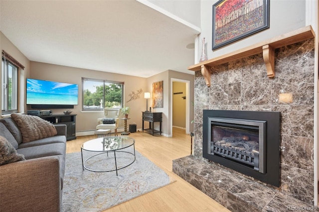 living room featuring a tile fireplace, a baseboard radiator, and light hardwood / wood-style floors