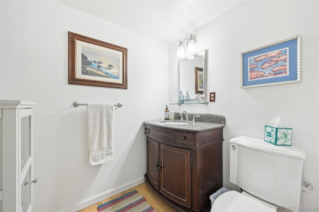 bathroom with toilet, vanity, and wood-type flooring