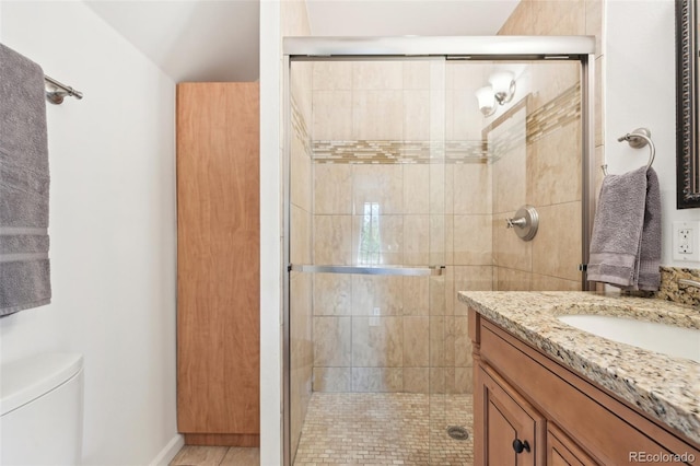 bathroom with an enclosed shower, vanity, and toilet