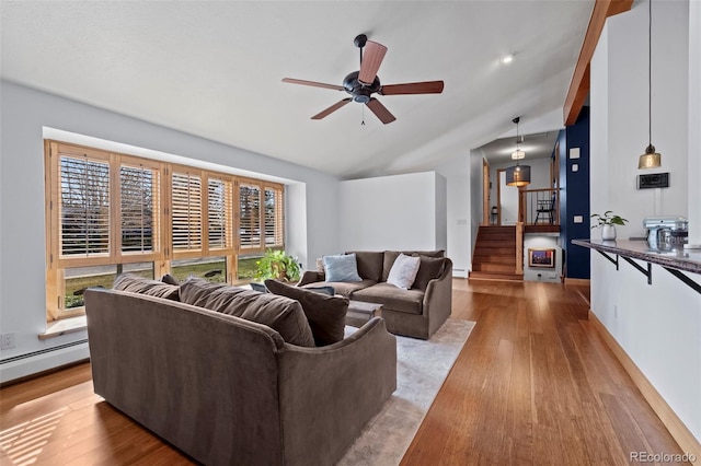 living area featuring vaulted ceiling, stairs, a ceiling fan, and wood finished floors