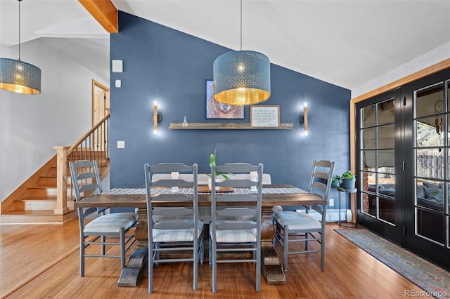 dining area with stairway, lofted ceiling, and wood finished floors