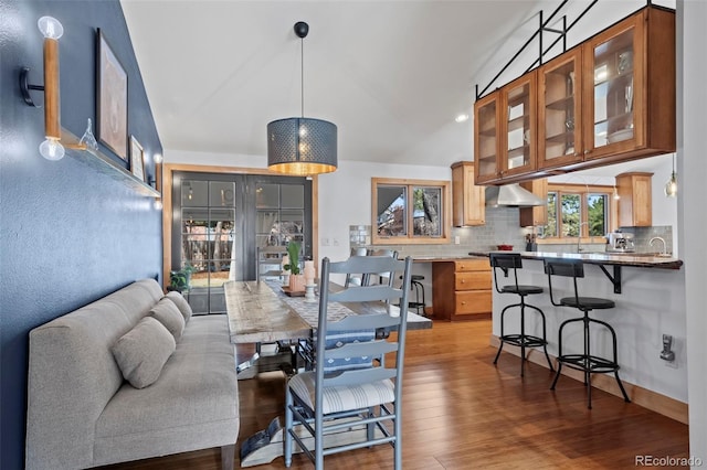 dining space featuring wood finished floors and vaulted ceiling